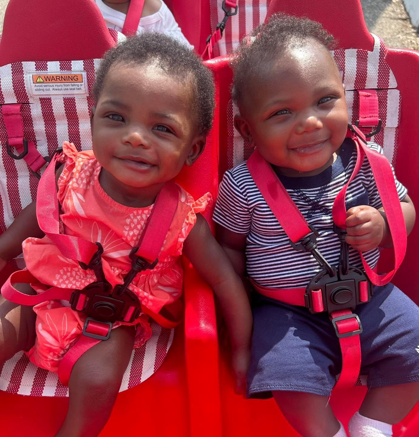 Two smiling infants in the Gulfport Academy stroller