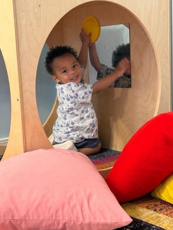 Toddler playing at a mirror activity station